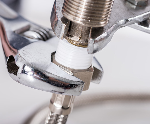 close-up of a wrench tightening a pipe connection showcasing plumbing mechanics with elements related to the 13 essential tools for repairs