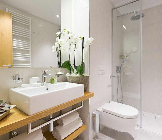 modern bathroom design featuring a sleek sink with wooden shelf fresh orchids and neatly stacked towels showcasing twelve elegant details in decor