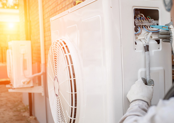 technician connecting outdoor air conditioning unit wiring with sunlight in background six maintenance tips for efficiency