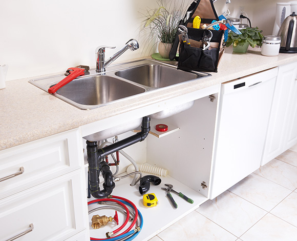 kitchen sink with plumbing tools and supplies organized under the counter including wrenches hoses and a toolbox for home repair 4 plumbing tips and tricks