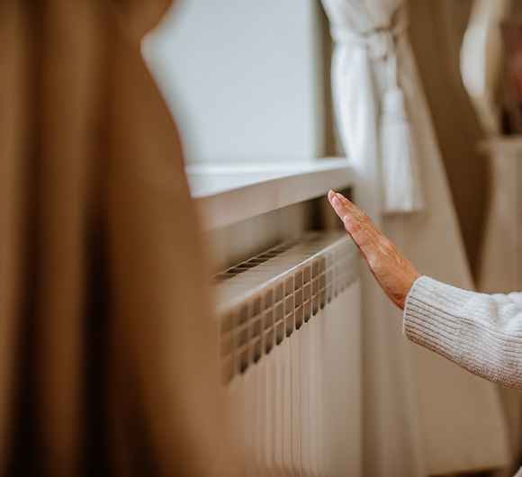 person gently touching a radiator in a cozy room with soft curtains and natural light warmth 4 home comfort