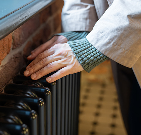 person gently touching a vintage radiator in a cozy setting maintaining warmth in three ways
