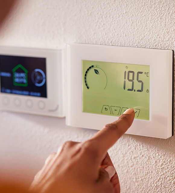 person adjusting a digital thermostat displaying 19.5 degrees showing energy efficient smart home control options