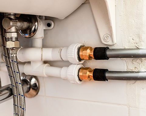 plumbing pipes with connectors and fittings in a wall bathroom sink area featuring three types of pipes