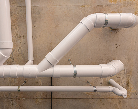 white PVC pipes arranged in various angles on a wall showcasing plumbing infrastructure and design five pipes system components