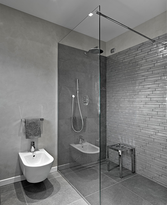 modern gray bathroom with glass shower, silver fixtures and a bidet, featuring two functional areas and sleek design elements