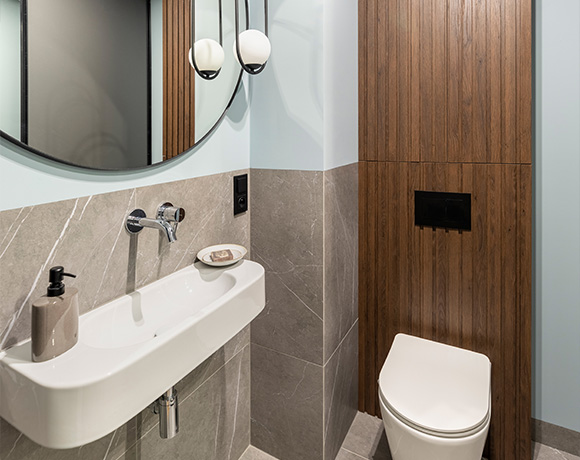 modern bathroom design with round mirror minimalist style featuring gray and wood accents and a sleek toilet essential design elements for small spaces 2